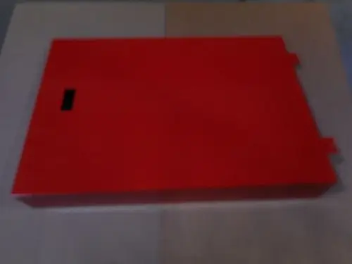 Rote Verkleidung auf hellen Untergrund, ohne erkennbare Maße, möglicherweise von Remeha. Die Verkleidung hat eine rechteckige Form mit einem kleinen schwarzen Element.